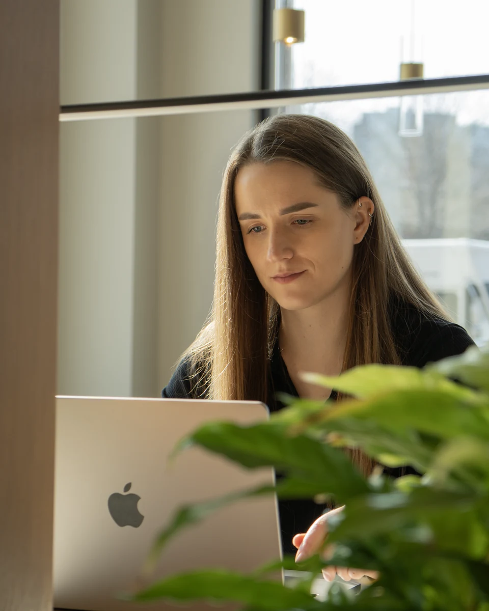 Nadia Dolot working on a laptop by a window