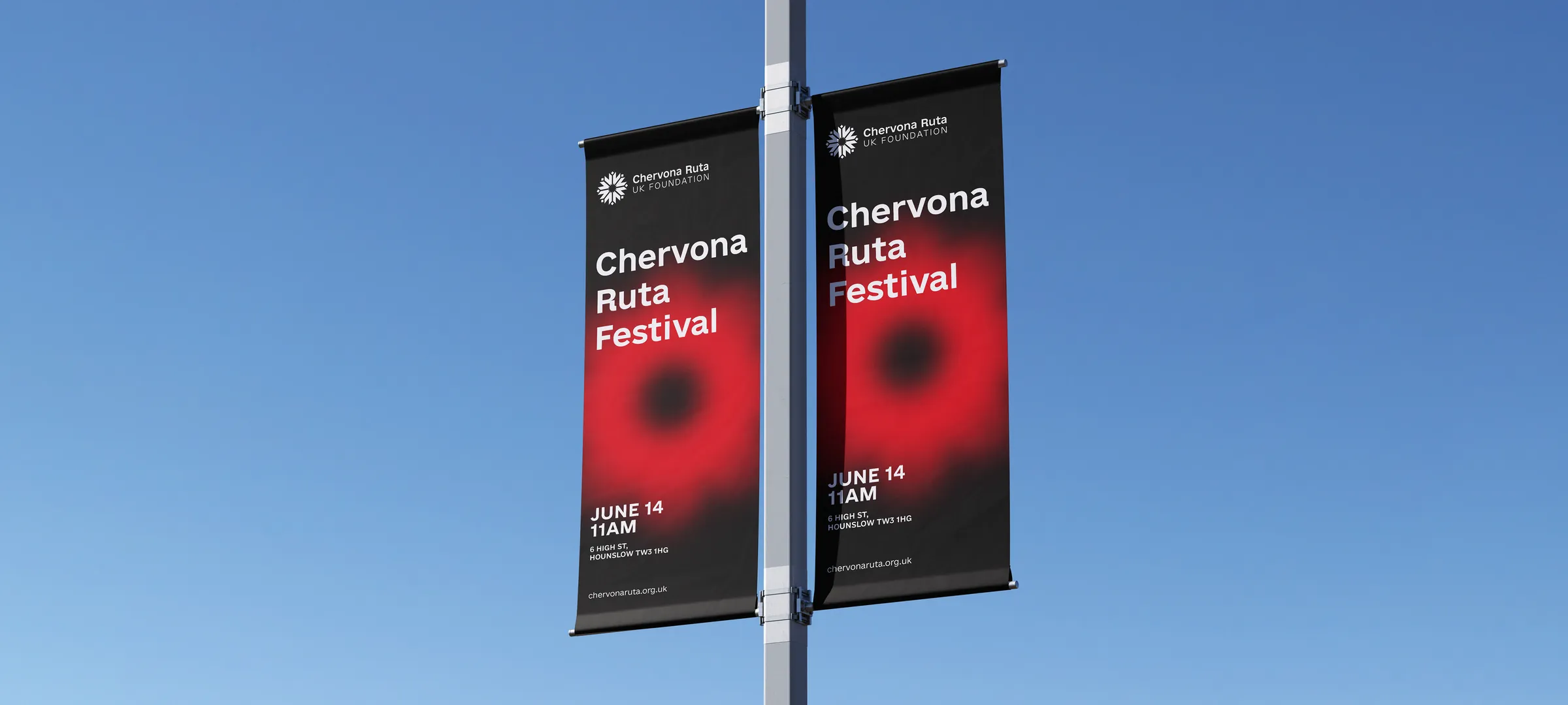 Two black street banners on a lamppost against a blue sky, reading Chervona Ruta Festival, each with the logo and a soft red flower graphic