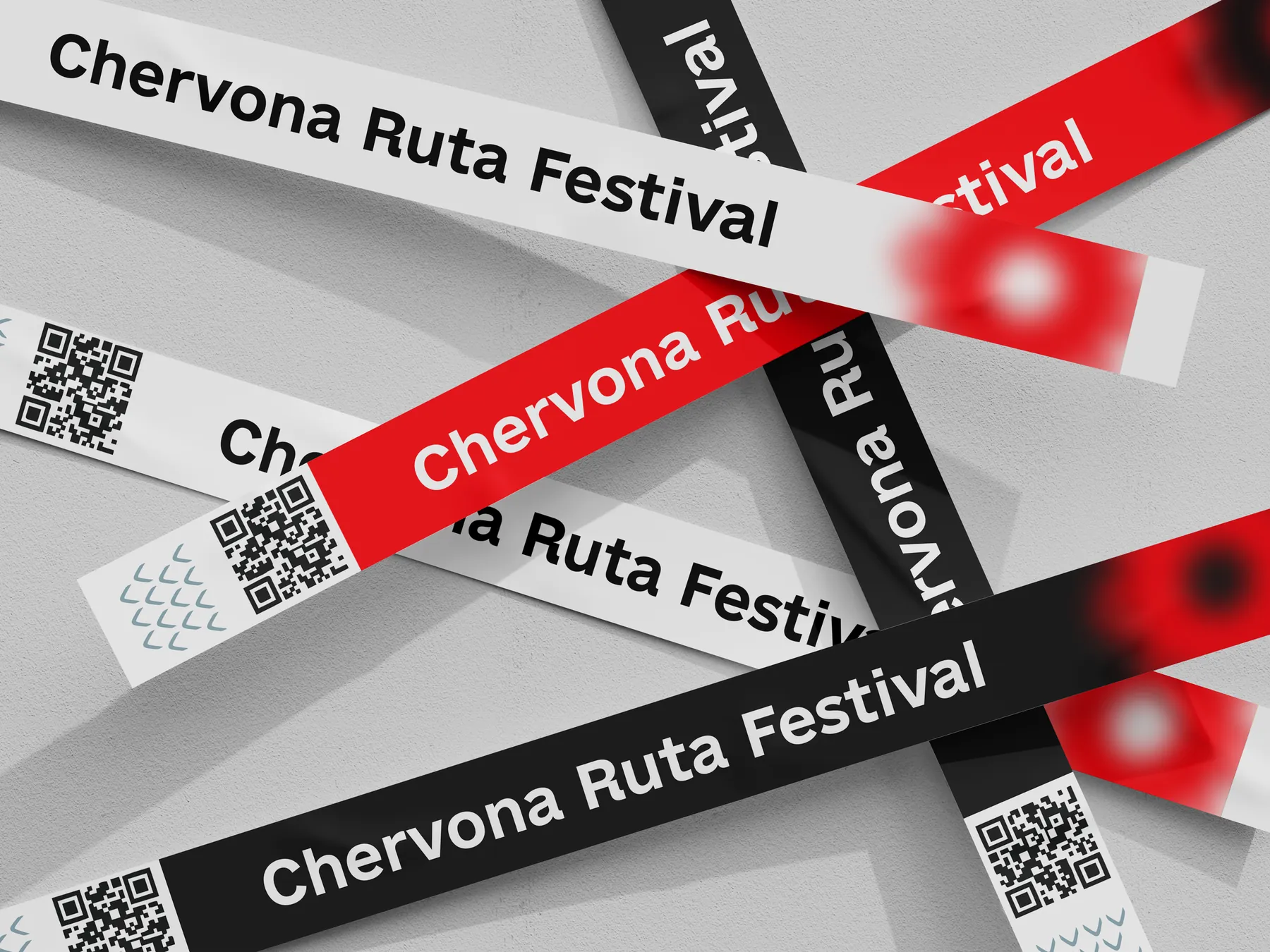Festival wristbands in white, red and black printed with Chervona Ruta Festival and a QR code, piled on a concrete wall