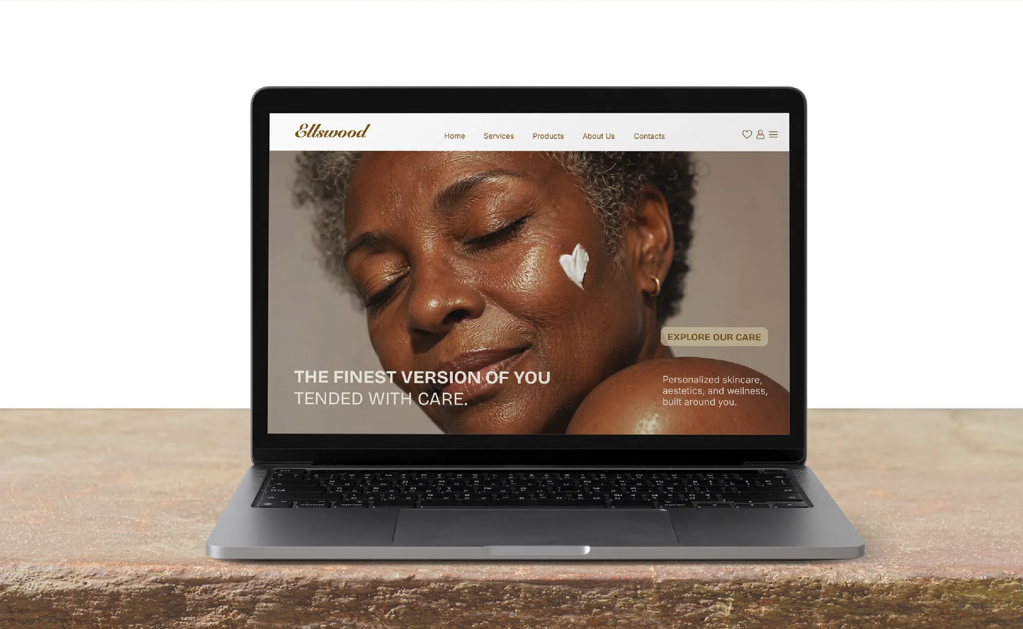 A laptop on a stone ledge showing the Ellswood website: 'The finest version of you, tended with care.'