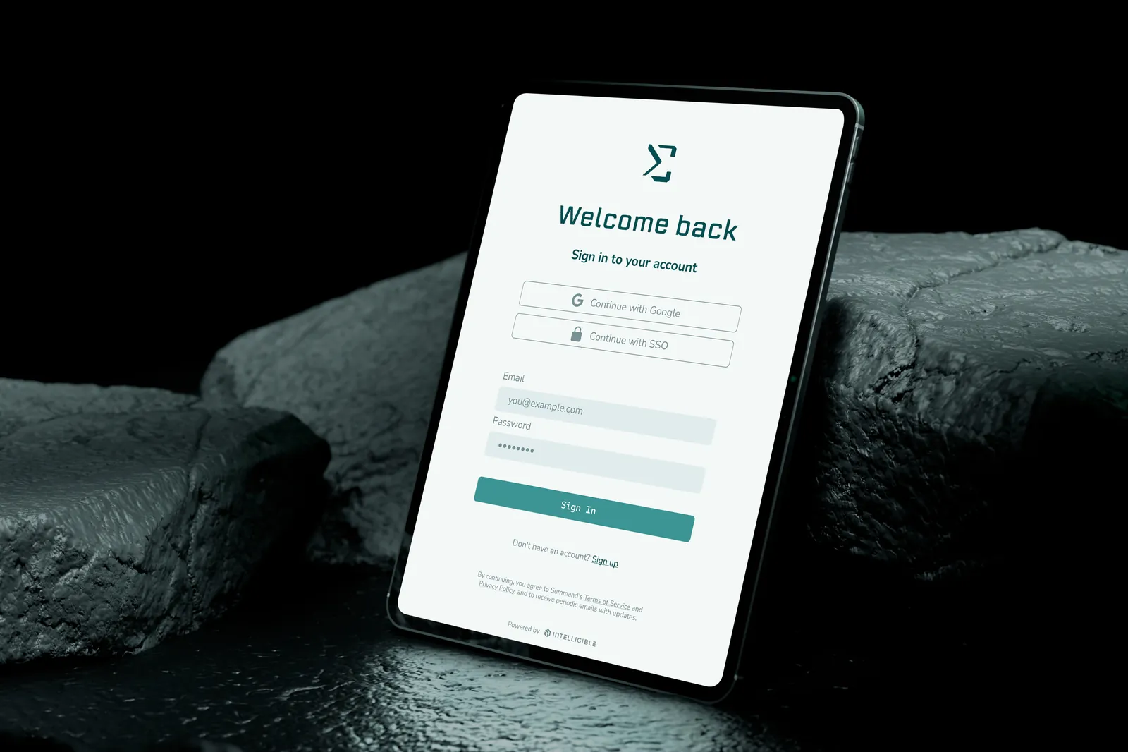 A tablet resting on dark rock, showing the Summand app's sign-in screen with the broken-sigma icon