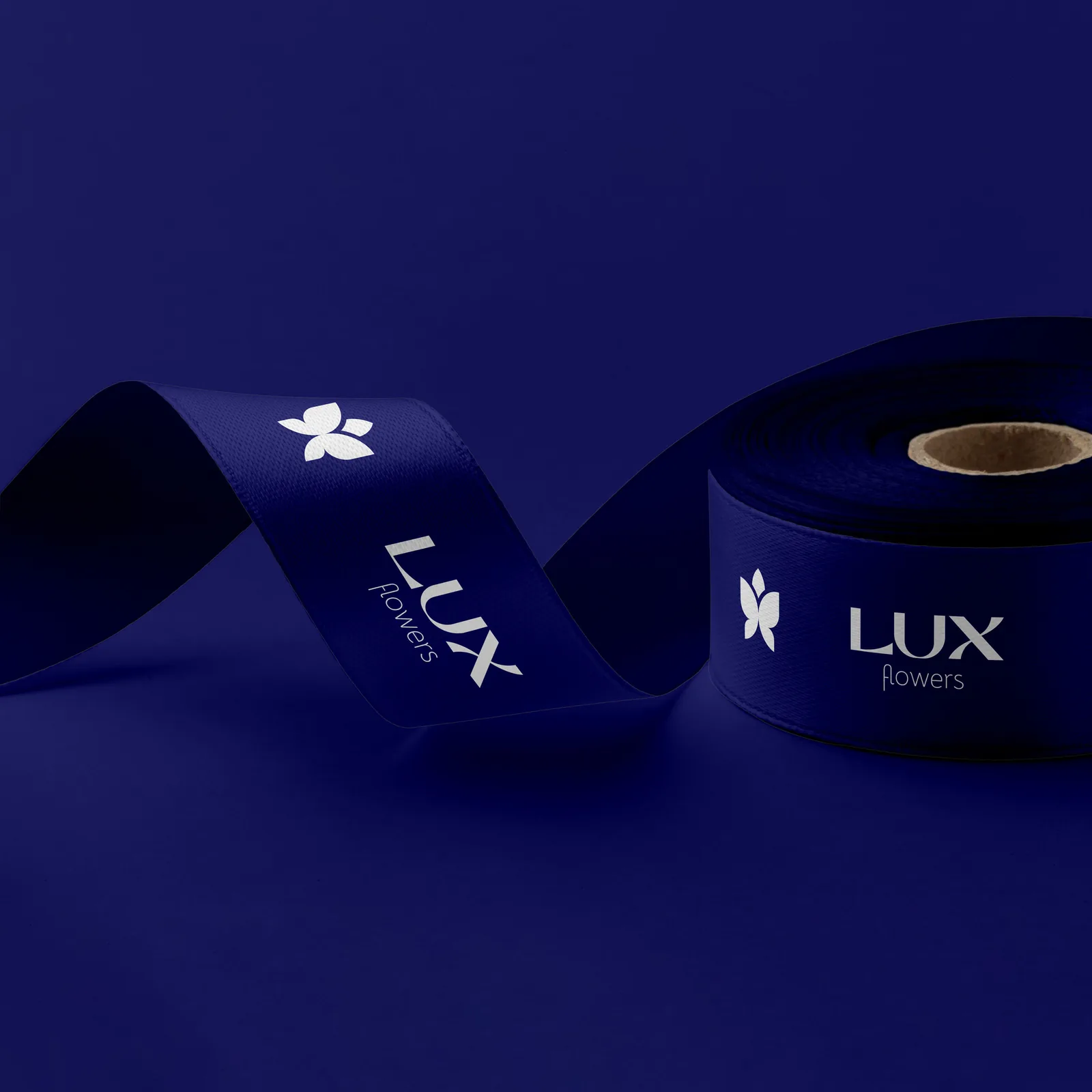 Navy satin ribbon printed with the Lux Flowers butterfly and wordmark