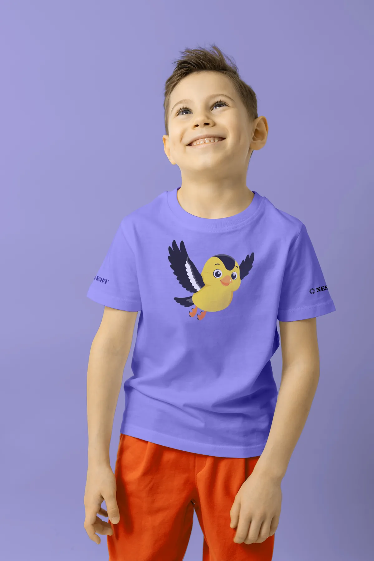 A smiling boy in a Periwinkle T-shirt printed with the flying goldfinch mascot