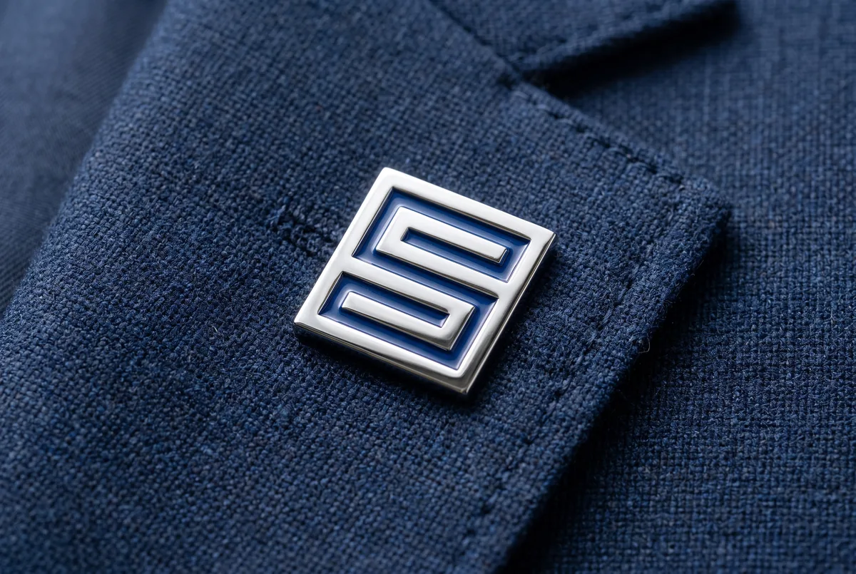 Enamel lapel pin bearing the logomark