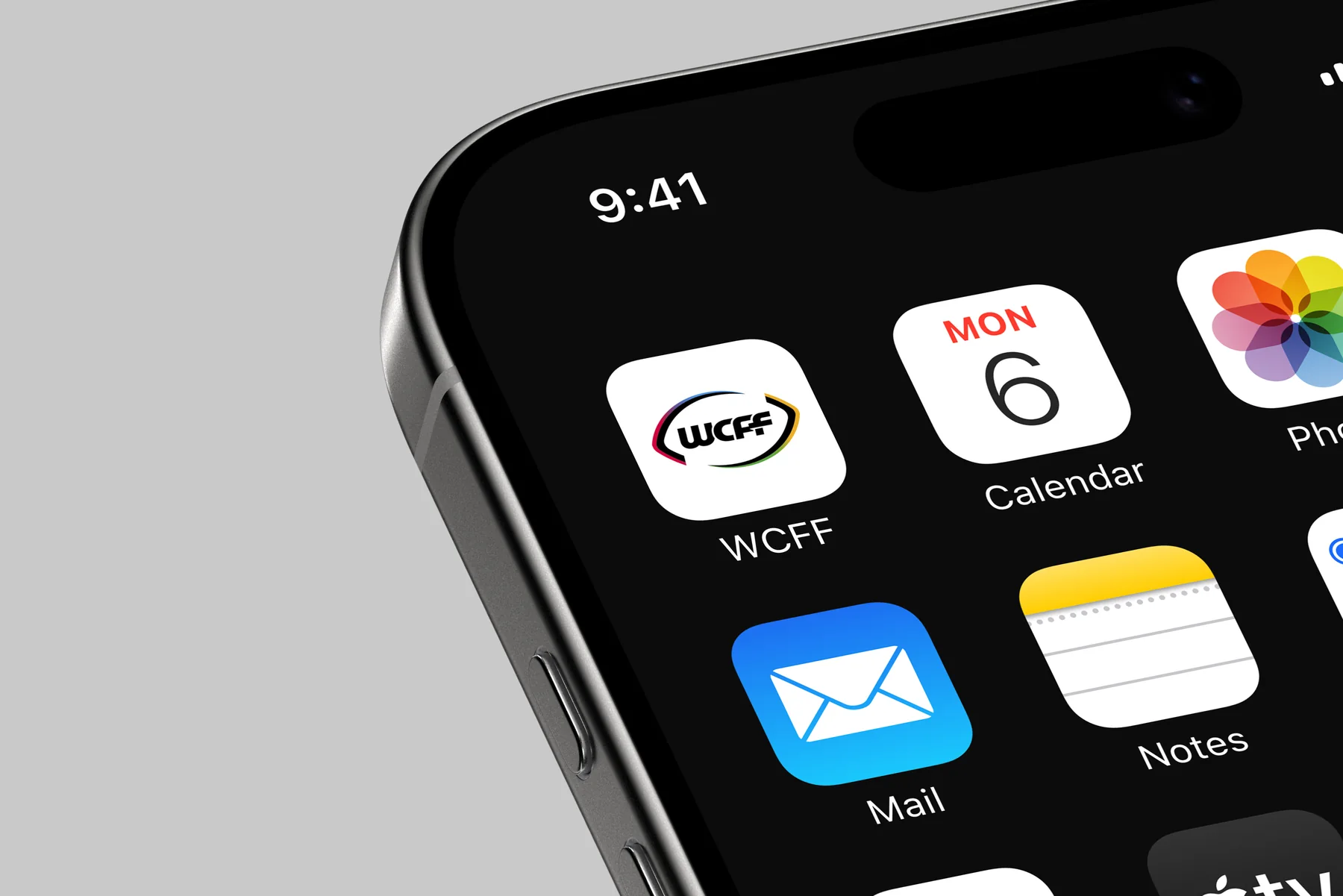 An iPhone home screen with the WCFF app icon, the solid-colour logo on white, next to Calendar and Mail