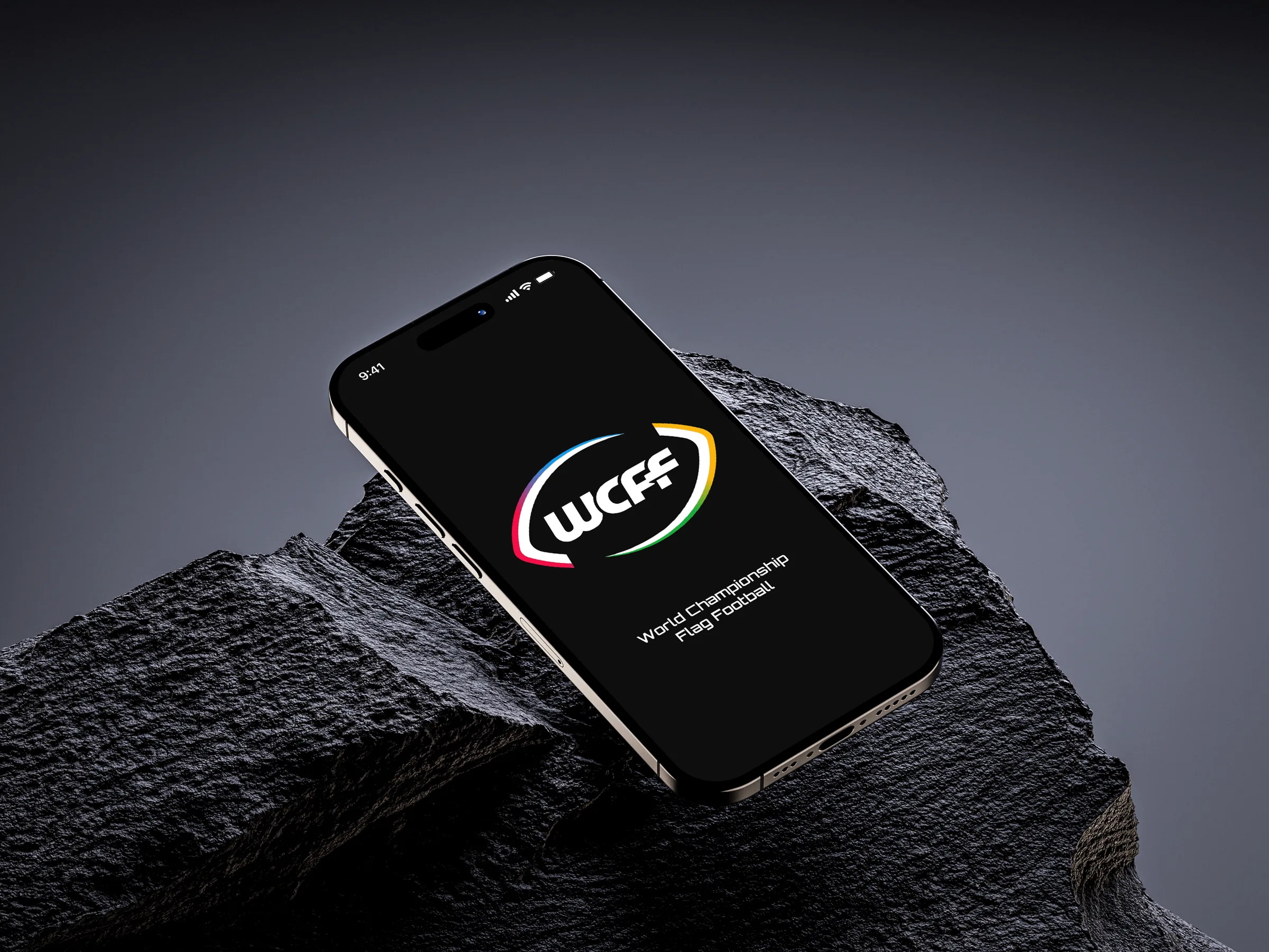 An iPhone resting on dark rock, its screen showing the WCFF logo with the full name, World Championship Flag Football, underneath